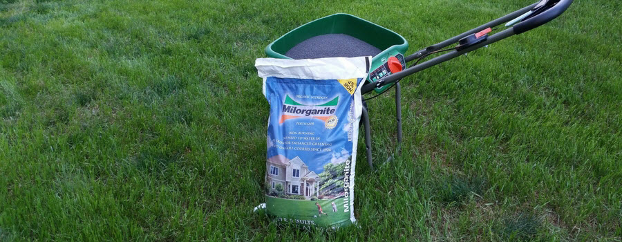 Bag of Milorganite Fertilizer in a spreader in lawn